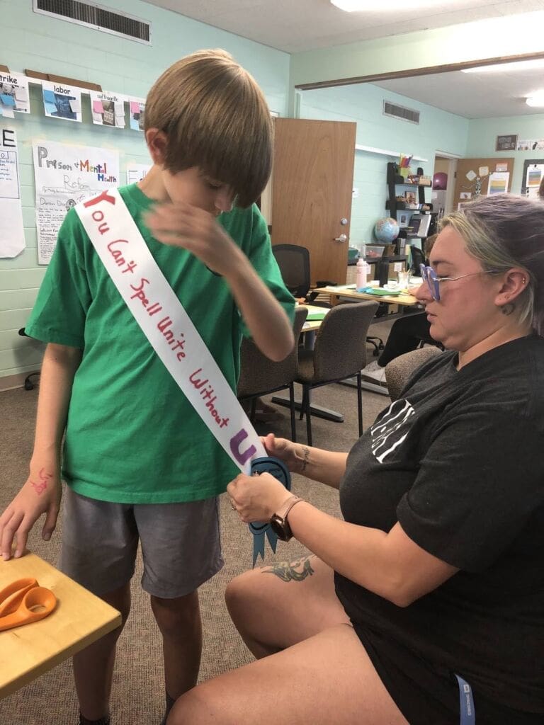 Teacher helping student wear banner 