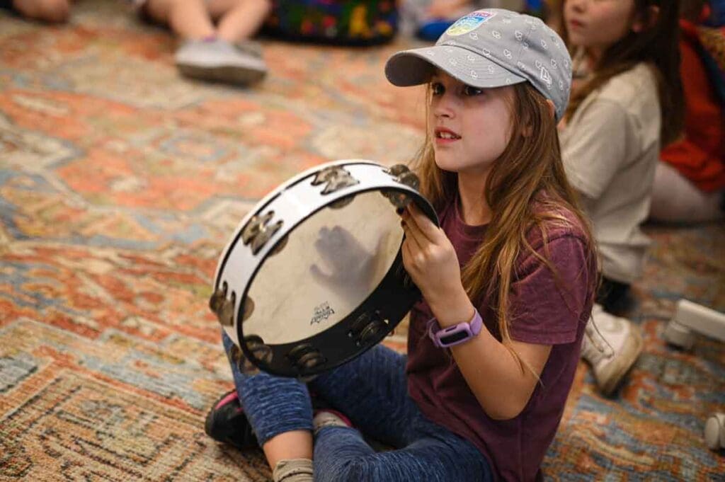 Third grade student plays  tambourine in micro school class.