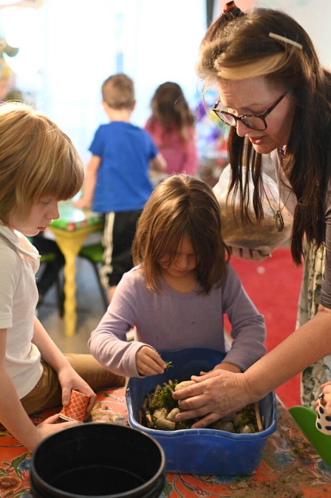 Teacher helping students with nature project.