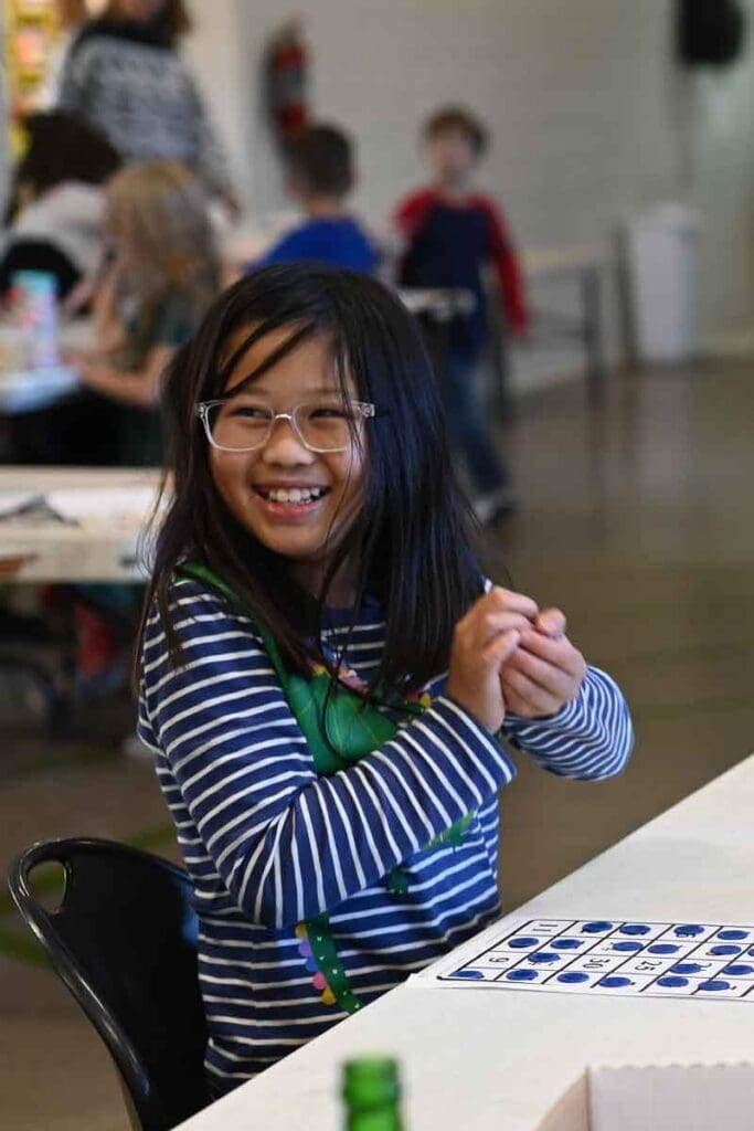 Girl smiles as she plays math pentathlon game at progressive micro school.