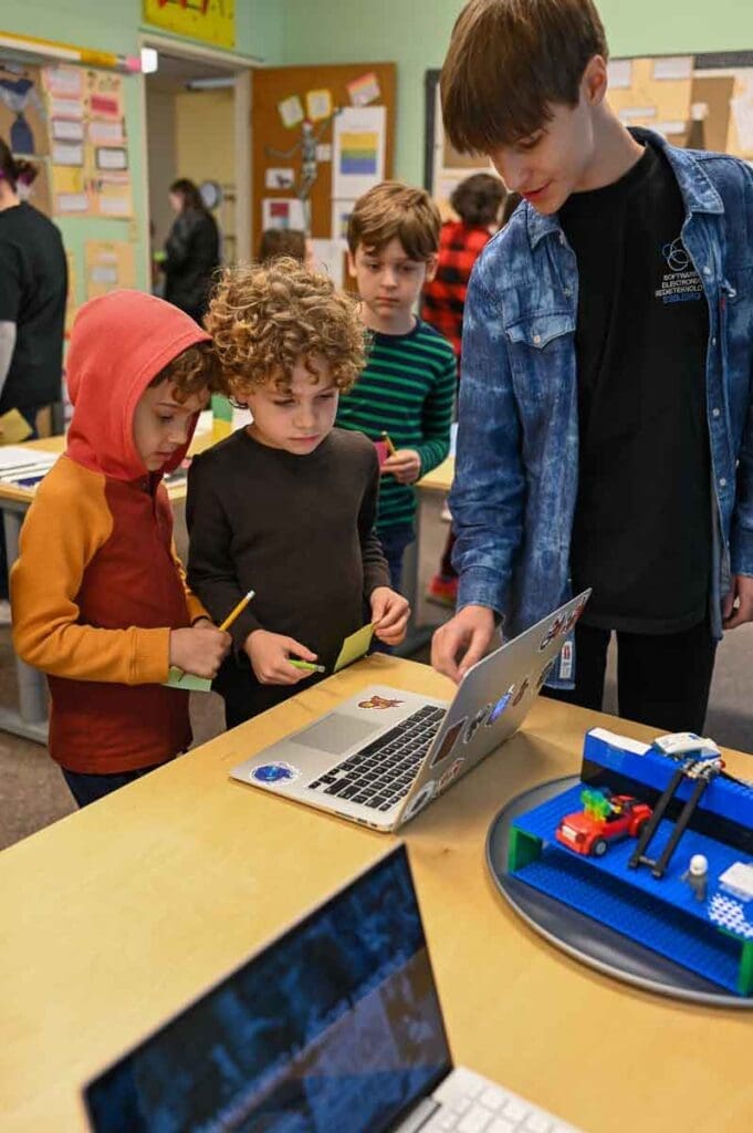 Middle schooler shows second graders computer at homeschool coop.