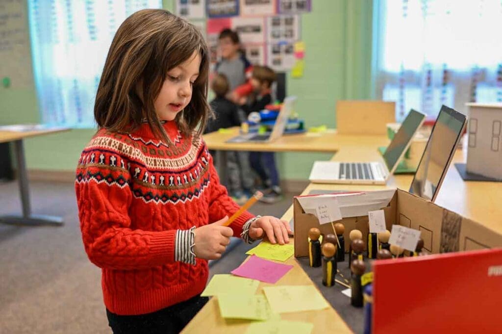 Kindergartener inspects middle school history project made with wooden figurines.