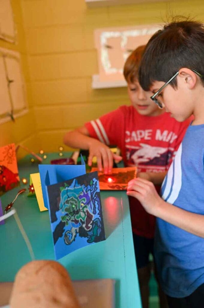 Two elementary boys =at STEM school look at project as it lights up.