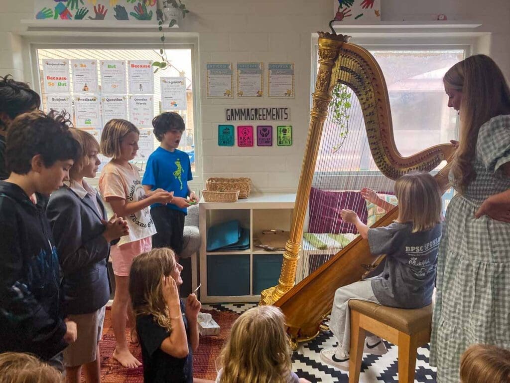 Small class surrounds guest speaker with harp at part-time school.