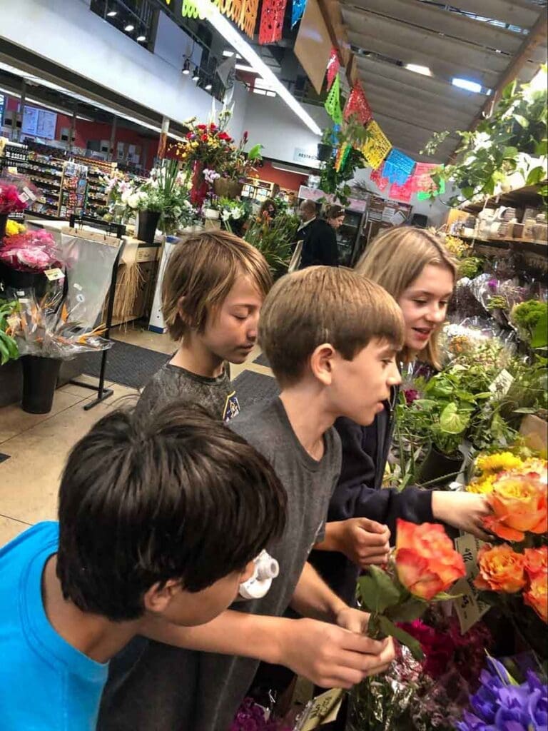 Progressive school students look at flowers at grocery store.