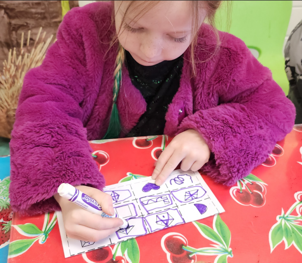 Private school kindergarten student works hard with marker and paper.